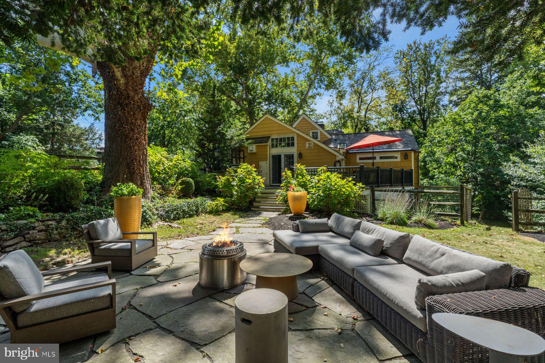 2472 River Road New Hope, PA 18938 - Photo 17 of 50 a view of a patio with couches table and chairs under an umbrella with large trees