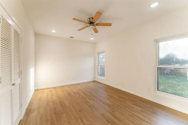 a view of empty room with wooden floor and fan