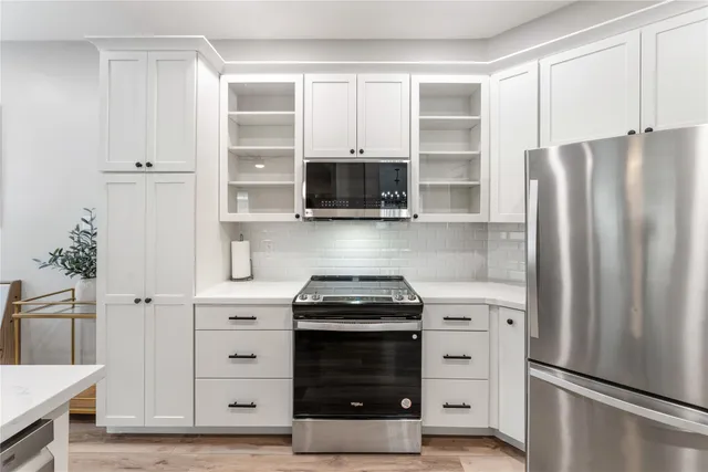 a kitchen with stainless steel appliances white cabinets and a refrigerator