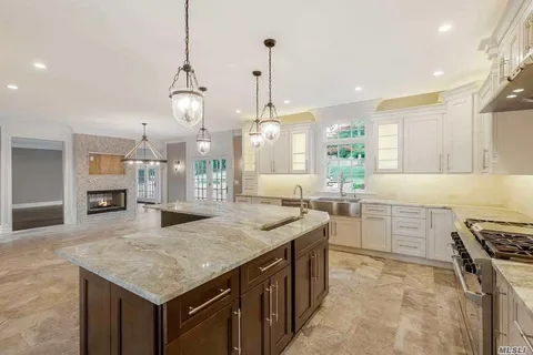 a kitchen with a stove a sink a center island a counter top space and living room view