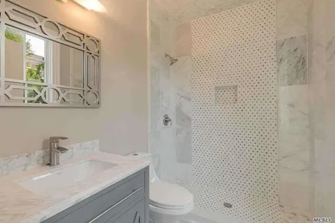 a bathroom with a granite countertop sink a toilet and shower