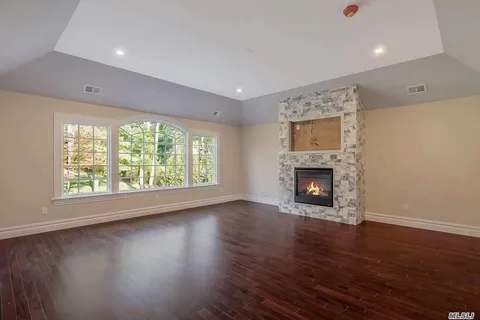 an empty room with wooden floor a fireplace and windows