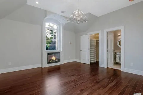 a view of an empty room with wooden floor fireplace and a window