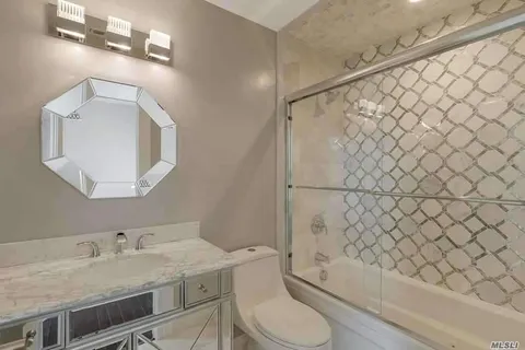 a bathroom with a granite countertop bathtub sink vanity mirror and toilet