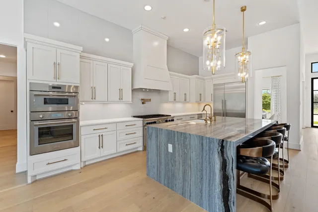 a kitchen with stainless steel appliances granite countertop a stove top oven a sink dishwasher a dining table and chairs with wooden floor