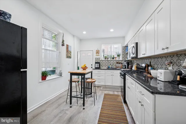 a kitchen with stainless steel appliances granite countertop a stove a sink dishwasher and a refrigerator with wooden floor