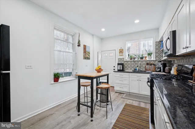 a room with stainless steel appliances kitchen island granite countertop a sink a stove a dining table and chairs