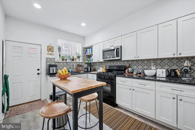 a kitchen with stainless steel appliances granite countertop a stove a refrigerator a sink a microwave and white cabinets