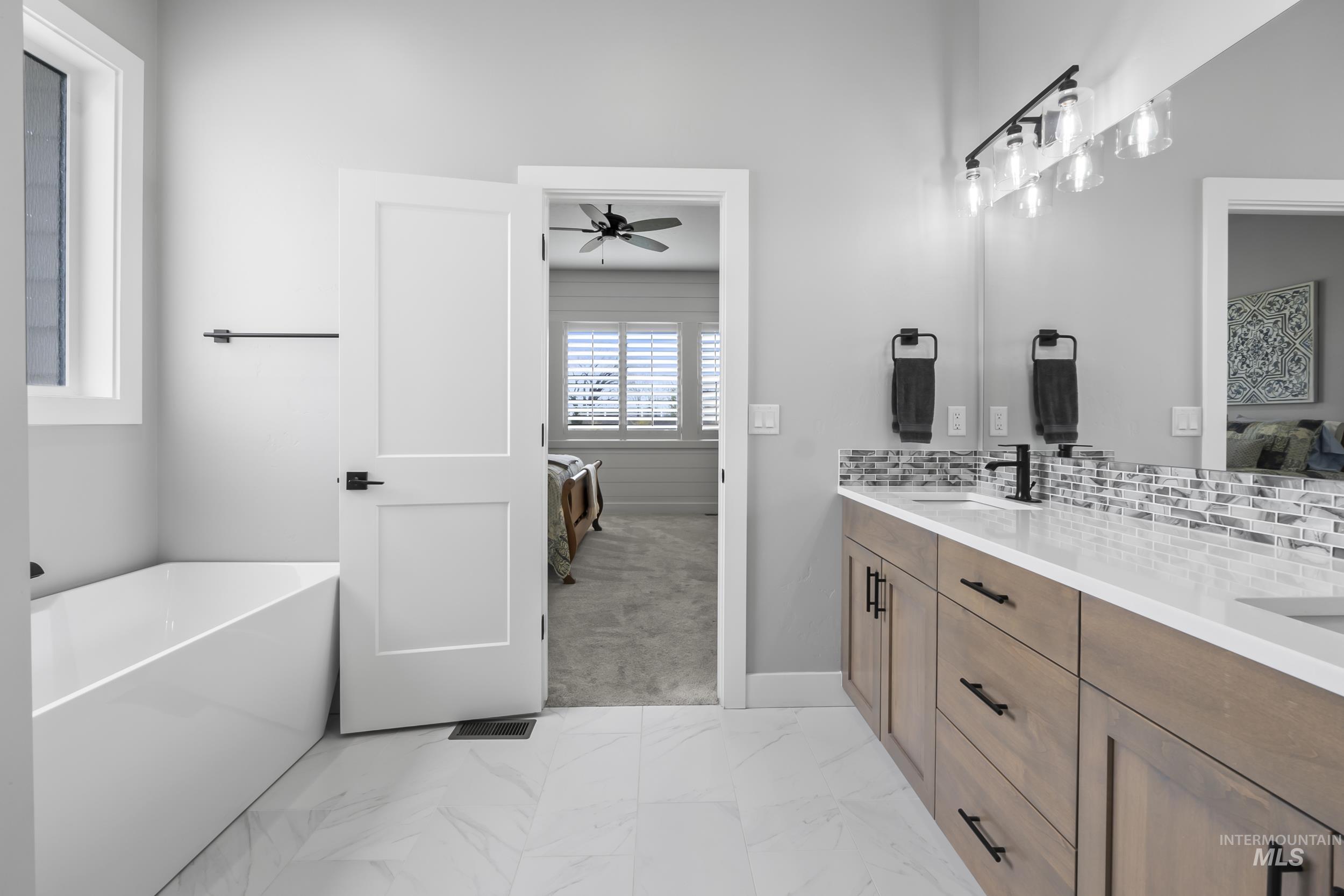 24696 Regal Road Middleton, ID 83644 - Photo 11 of 24 Bathroom featuring ensuite bath, light marble finish floors, a freestanding bath, double vanity, and light carpet