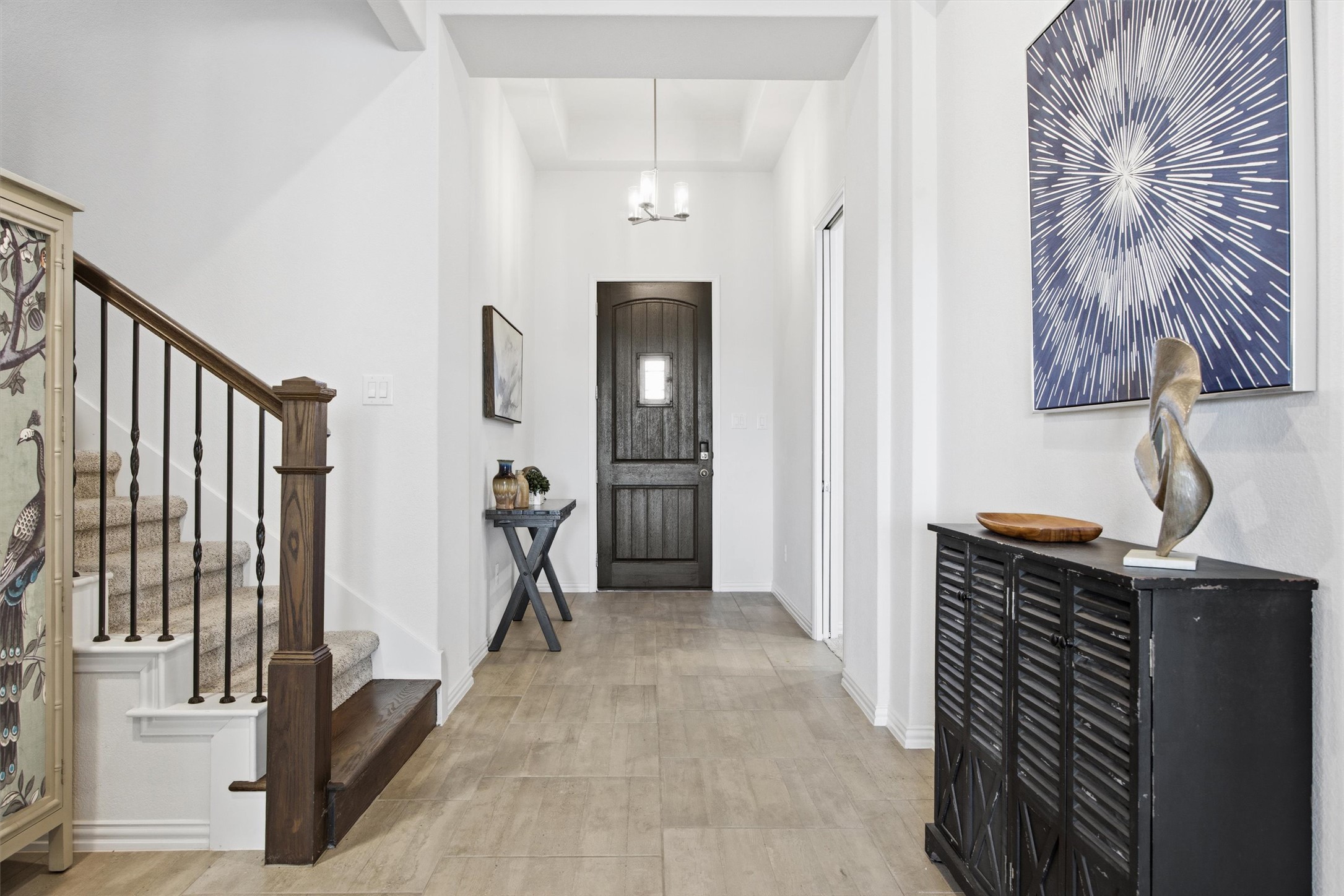 192 Raptor Beak Way Cedar Creek, TX 78612 - Photo 6 of 38 Entryway featuring wood-look tile flooring, a dark wood entry door with a privacy window, and a grand staircase with dark wood banister and iron balusters