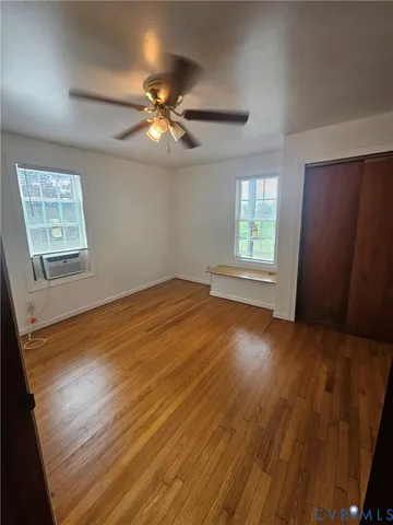 a view of empty room with wooden floor and fan
