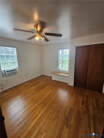 a view of empty room with wooden floor and fan