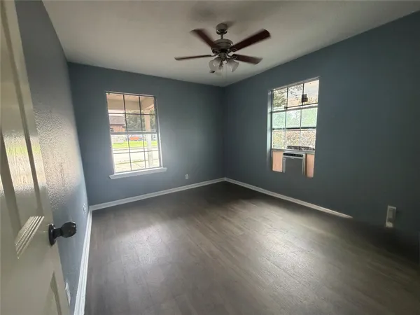 an empty room with wooden floor and windows