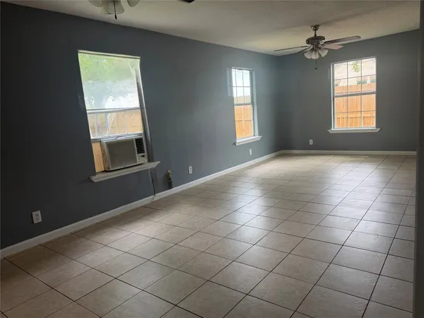 an empty room with windows and fan