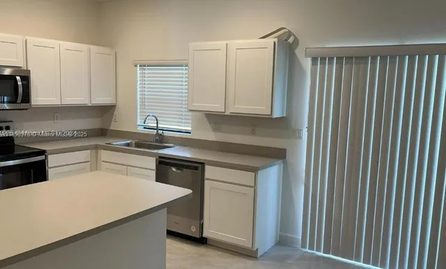 a kitchen with stainless steel appliances granite countertop a refrigerator a sink a stove a microwave and island