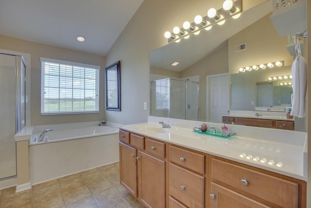 3018 Langston Place Spring Hill, TN 37174 - Photo 24 of 33 a spacious bathroom with a granite countertop double vanity sink a large mirror a bathtub and next to a window