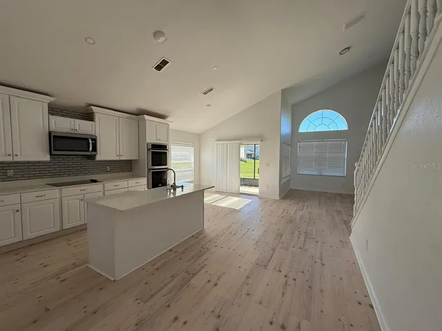 a large kitchen with cabinets wooden floor and stainless steel appliances