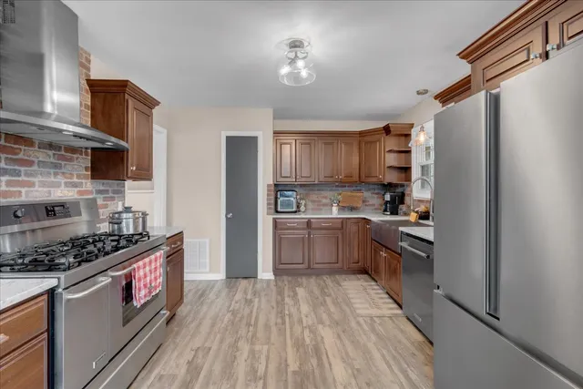 a kitchen with stainless steel appliances granite countertop a stove refrigerator and a sink