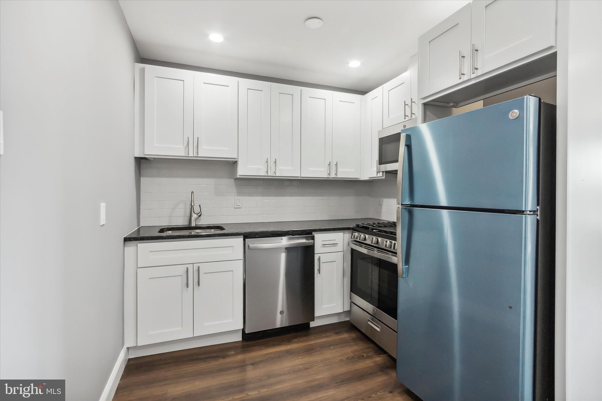 296 Greenough Street, Unit 2 Philadelphia, PA 19127 - Photo 8 of 24 a kitchen with stainless steel appliances granite countertop a refrigerator sink and white cabinets