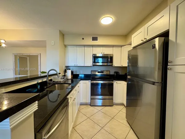 a kitchen with stainless steel appliances granite countertop grey cabinets a stove a sink and dishwasher