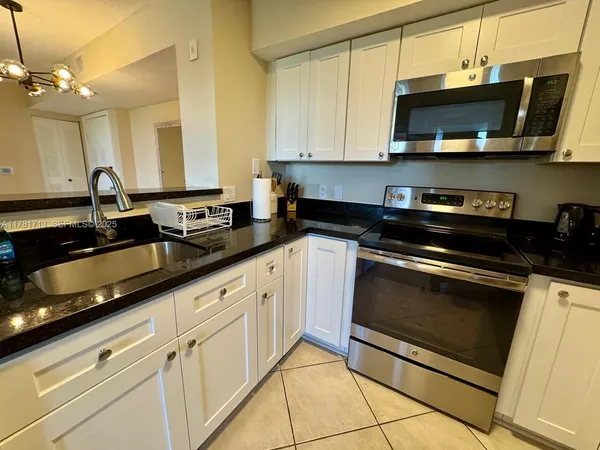 a kitchen with granite countertop white cabinets and a sink
