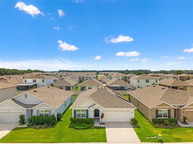 an aerial view of residential houses with yard and mountain view in back