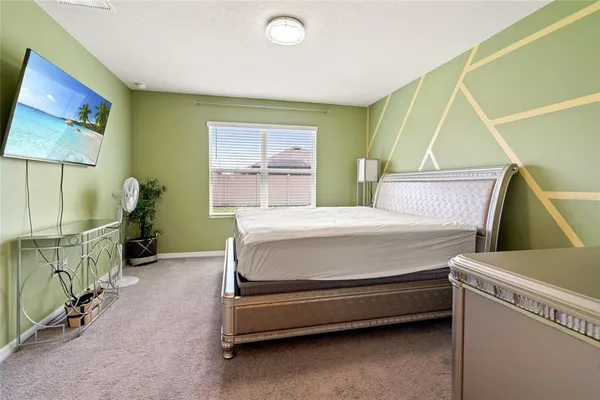 a bedroom with a bed and a flat tv screen on the dresser