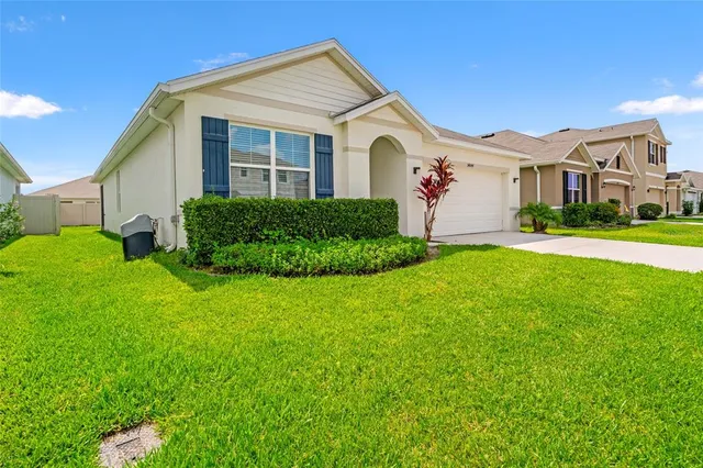 a view of a white house with a big yard and potted plants