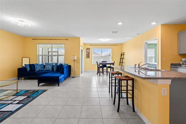 a living room with furniture a dining table and a piano next to a window