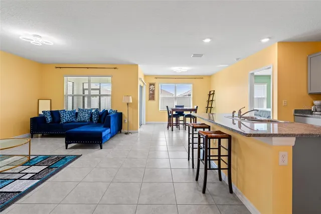 a living room with furniture a dining table and a piano next to a window