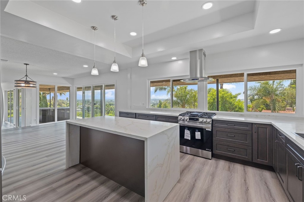 a kitchen with stainless steel appliances granite countertop hardwood floor sink stove large window and cabinets
