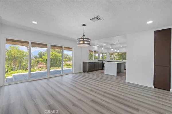 a kitchen with stainless steel appliances granite countertop a refrigerator a sink dishwasher a stove and white countertops with wooden floor