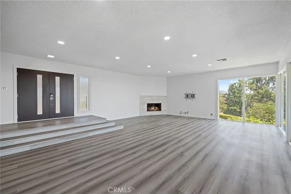 a view of an empty room with wooden floor and floor to ceiling window