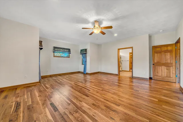 an empty room with windows and chandelier fan