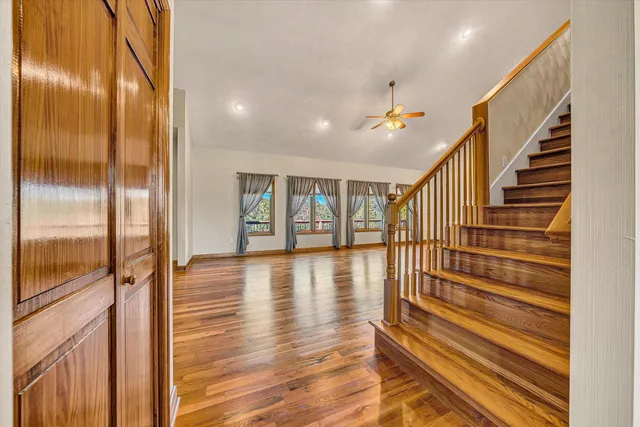 a view of empty room with wooden floor and fan