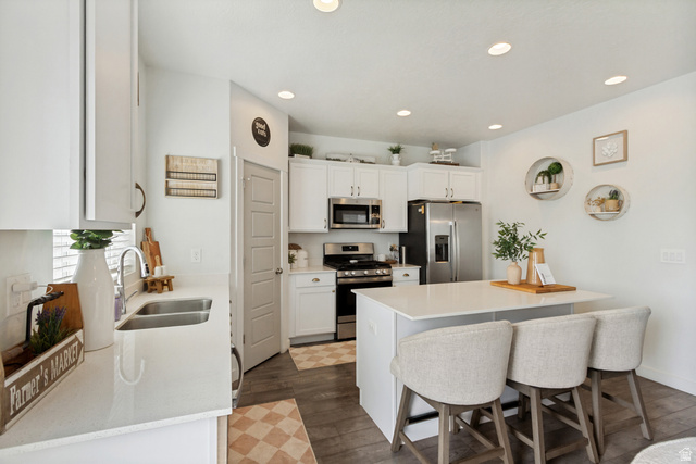 7693 West Mount Elinor Road Magna, UT 84044 - Photo 7 of 33 White cabinetry with brushed nickel hardware, stainless steel appliances, dual basin sink, central island, and wood-finish flooring