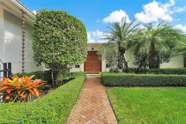 a front view of a house with a yard and fountain in middle