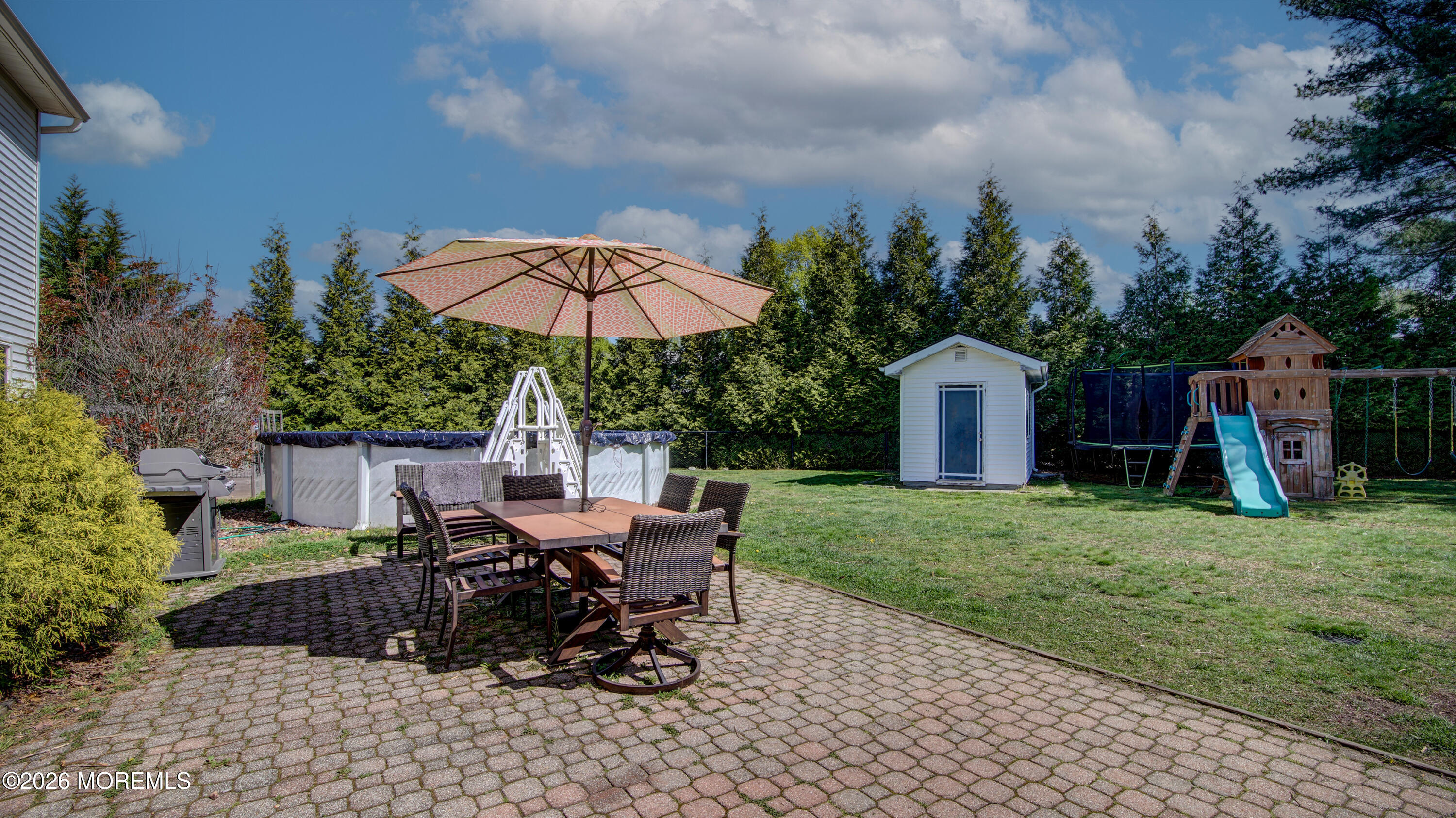 128 Starlight Road Howell, NJ 07731 - Photo 24 of 36 a view of a backyard with table and chairs under an umbrella with a barbeque grill and wooden fence