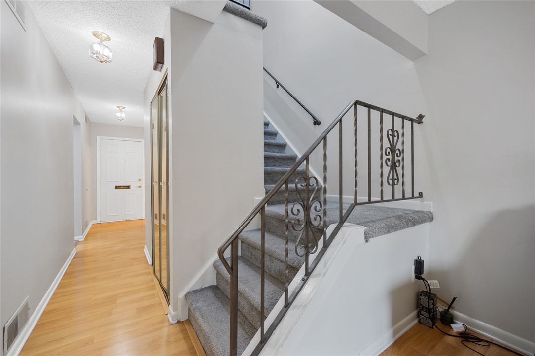 597 French Road Brighton, NY 14618 - Photo 11 of 24 Open stairway with a view toward the front door.