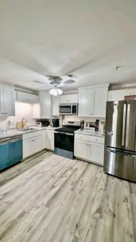 a kitchen with granite countertop white cabinets and stainless steel appliances