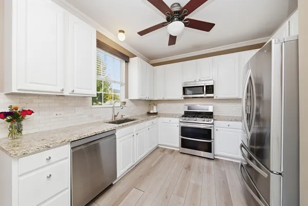 a kitchen with stainless steel appliances granite countertop a refrigerator stove a sink and dishwasher with wooden floor