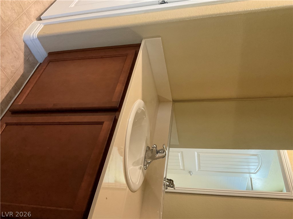 12 Jasmine Point Street Henderson, NV 89074 - Photo 8 of 15 A streamlined vanity with rich wooden cabinetry, a clean sink, and a well-placed mirror offers utility.