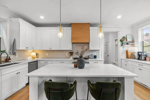 a kitchen with a stove a sink a refrigerator and white cabinets with wooden floor