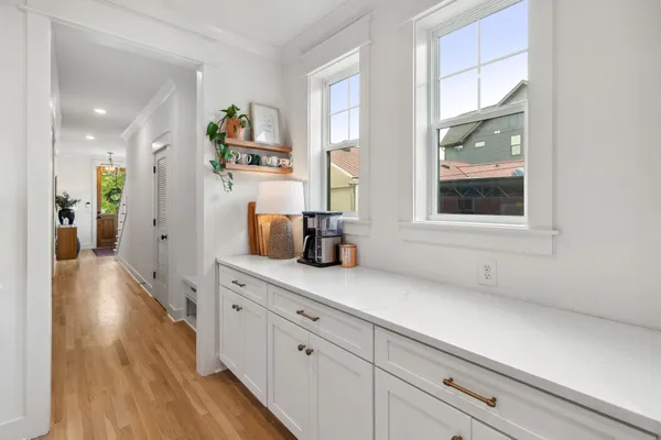 a hallway with white cabinets and wooden floor