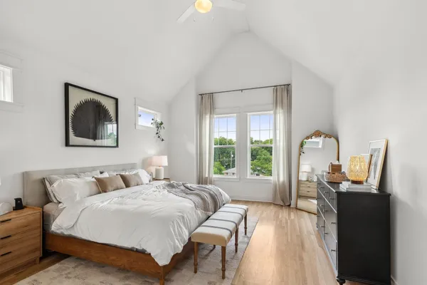 a bedroom with a bed large window with lamp and windows