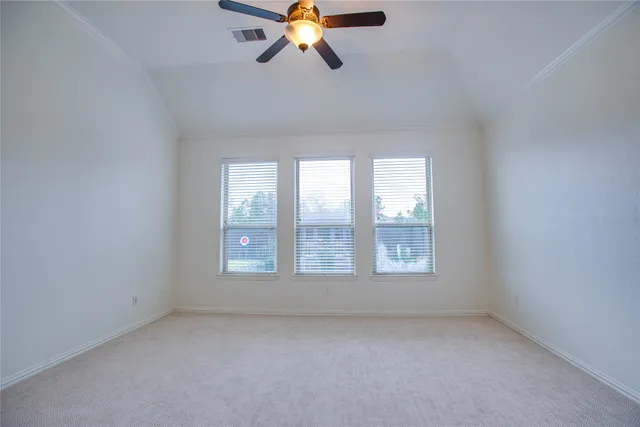 an empty room with chandelier fan and windows