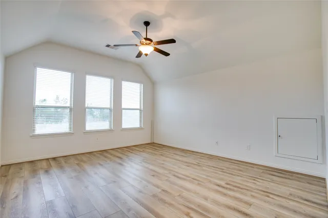 a view of empty room with wooden floor and fan