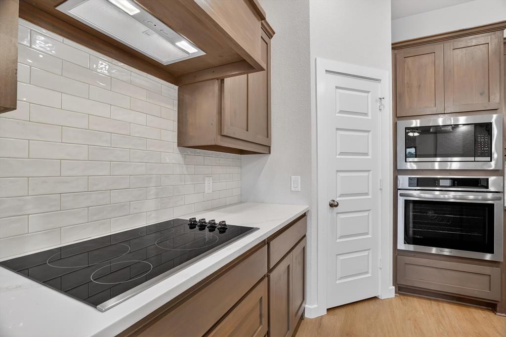 321 Skeen Peak Springtown, TX 76082 - Photo 10 of 37 Kitchen featuring light wood-finish cabinetry, white subway tile backsplash, white countertops, a built-in cooktop, and stainless steel double oven