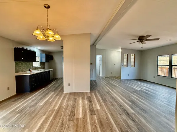 a view of a kitchen with a kitchen island wooden floor stainless steel appliances and a window