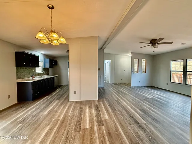 a view of a kitchen with a kitchen island wooden floor stainless steel appliances and a window